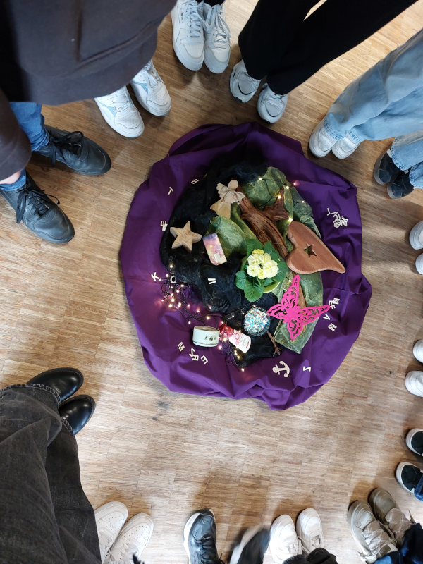 ein gefüllter lila Sack und drumherum Beine von Schülerinnen und Schülern