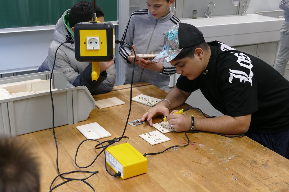 Schüler arbeiten mit dem Brennpeter auf Holzplatten